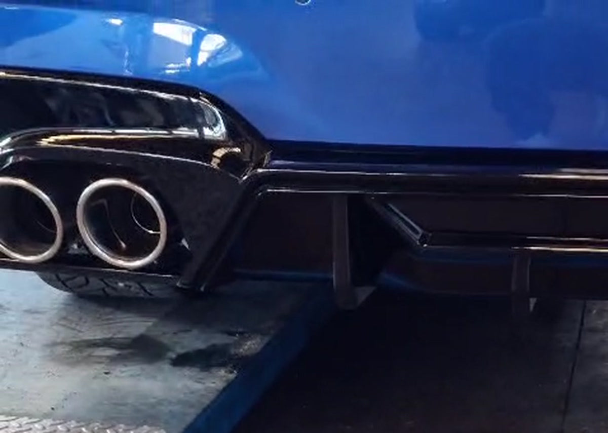 Blue BMW G20 330i on a workshop lift, rear bumper in frame showing four polished stainless steel exhaust tips of the new valved catback