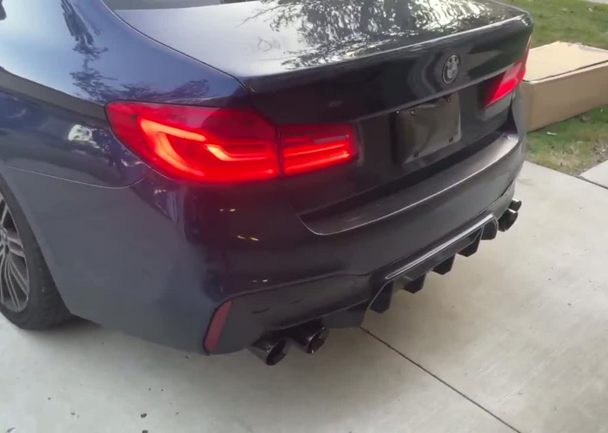 2018 BMW 540i G30 rear quarter in a driveway at night, LED tail light lit, aftermarket diffuser with quad exhaust tips