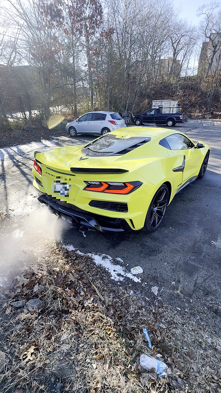 Yellow Chevrolet Corvette C8 Z06 rear view, quad center exhaust with titanium blue heat tint, valved titanium axle-back fitted, rear number plate pixelated for privacy