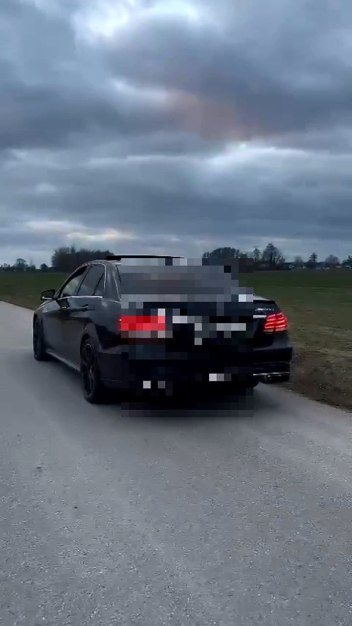 Black Mercedes-AMG E63 W213 on a narrow country road, valved SUS304 catback fitted, centre plate area pixelated for privacy